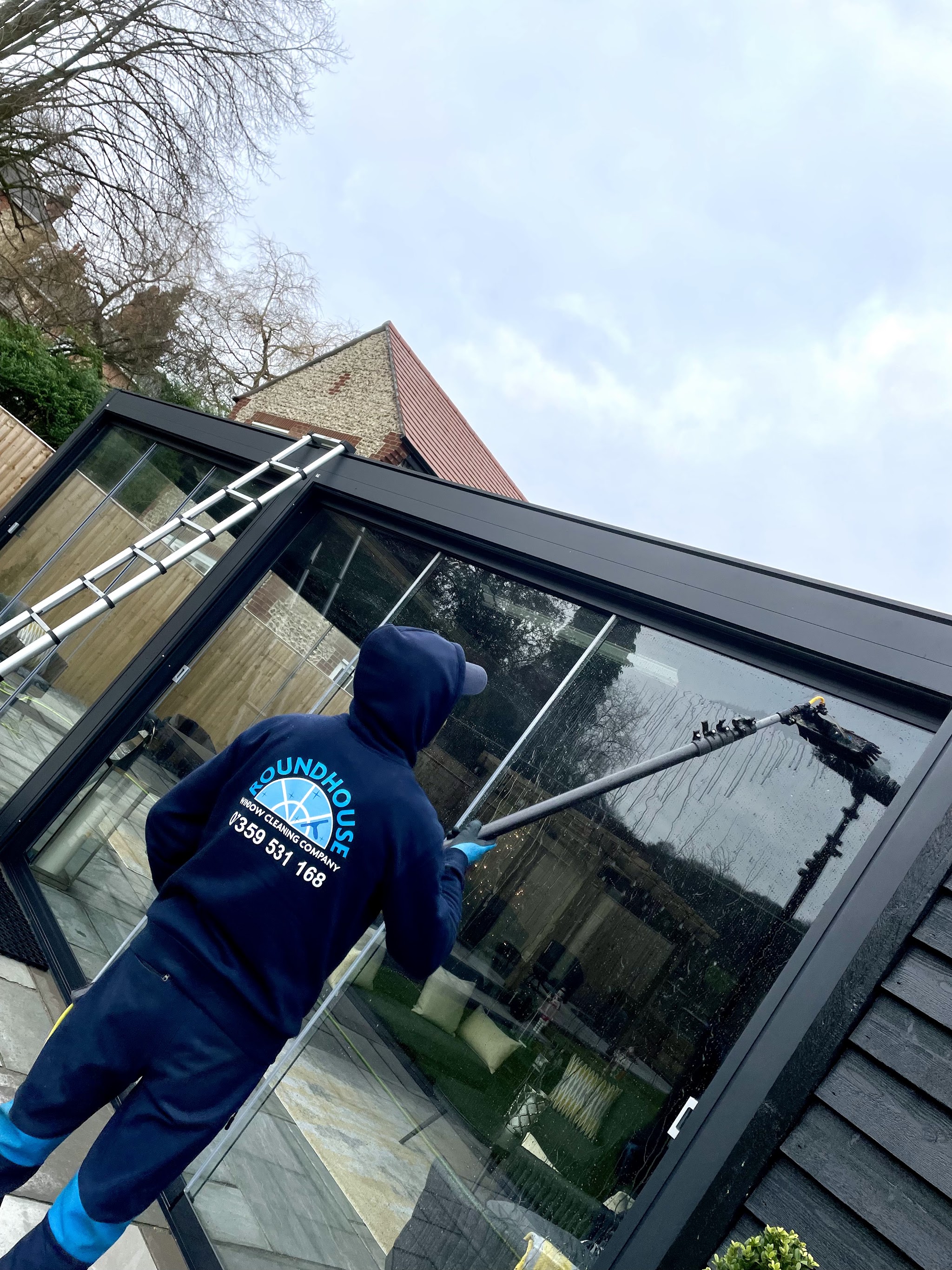 Cleaning a large pitched glass roof, with a ladder laid across the glazing bars