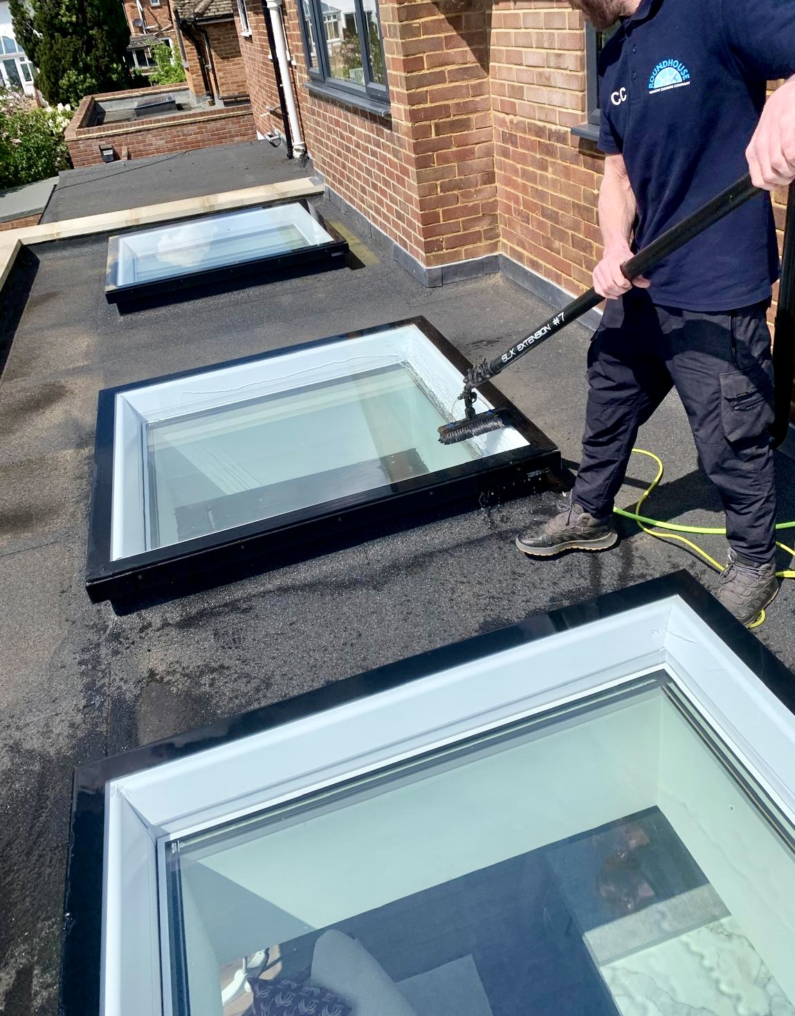 Cleaning the glass of flat-roof lantern skylights with a pole brush